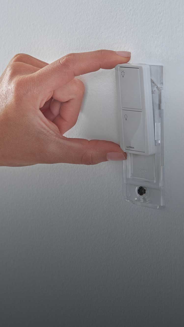 Pico smart remote being mounted to wall by woman with wallplate bracket