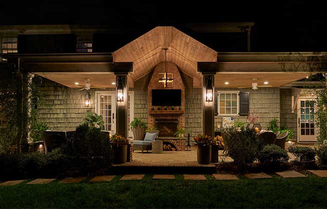 Patio outside house at nighttime, illuminated by lights.