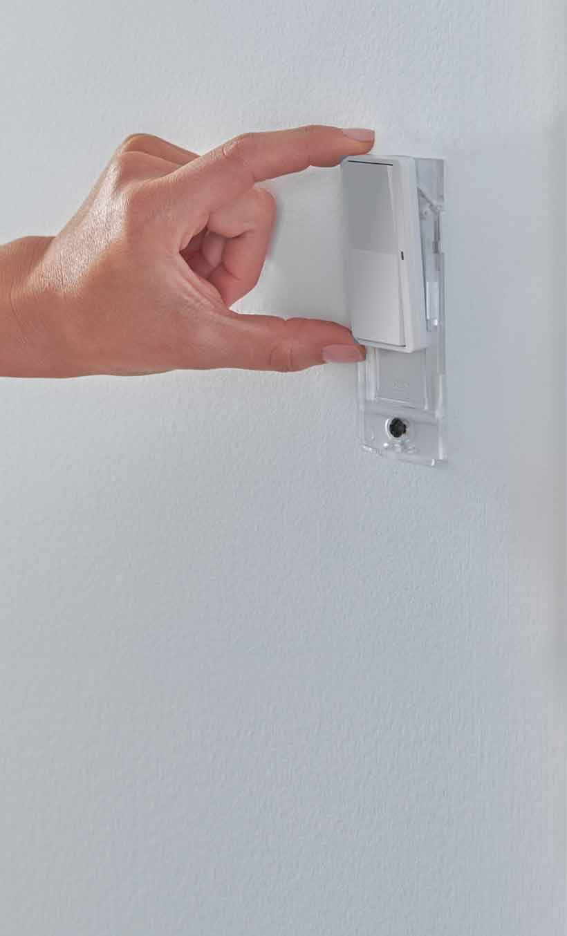 Female hand placing Pico paddle remote on wall with wallplate bracket