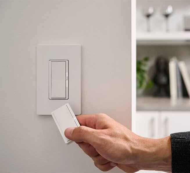 Contractor pairing a Pico paddle remote to a Diva smart dimmer switch on wall