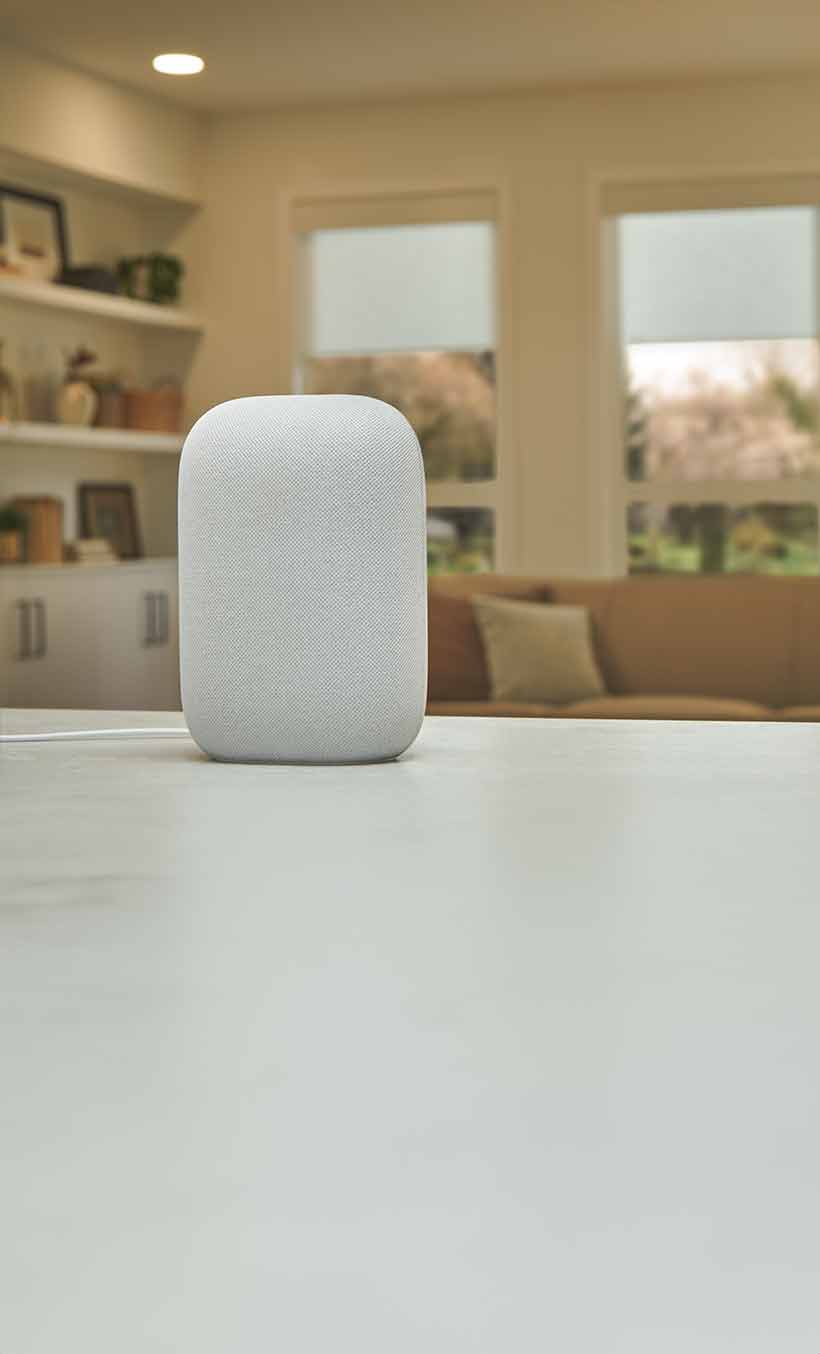 Illuminated Google smart speaker on countertopwith living room in the background