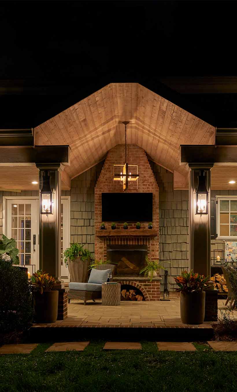 Patio outside house at nighttime, illuminated by lights.