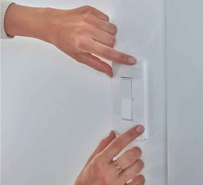 Woman snappping Claro wallplate onto the Pico paddle remote to complate wall mounting application