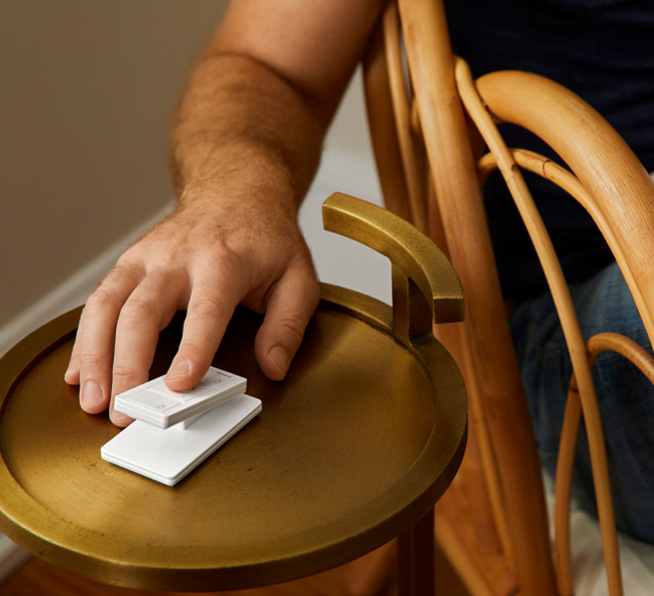 Man using 3-button with raise/lower Pico smart remote on side table