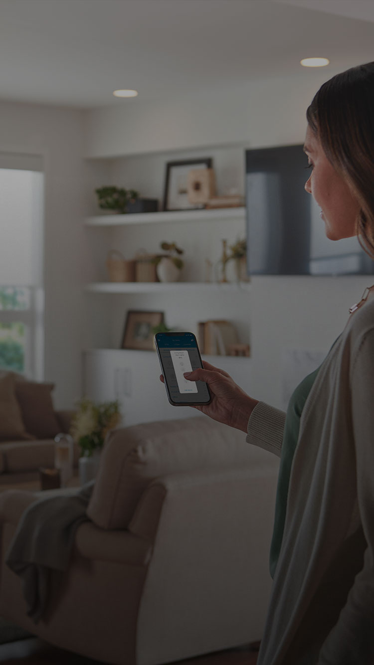 Woman controlling living room lights and shades with Lutron App