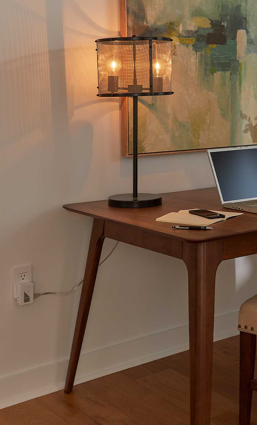 Table lamp sitting on desk, plugged into wall with the Lamp Dimming Smart Plug