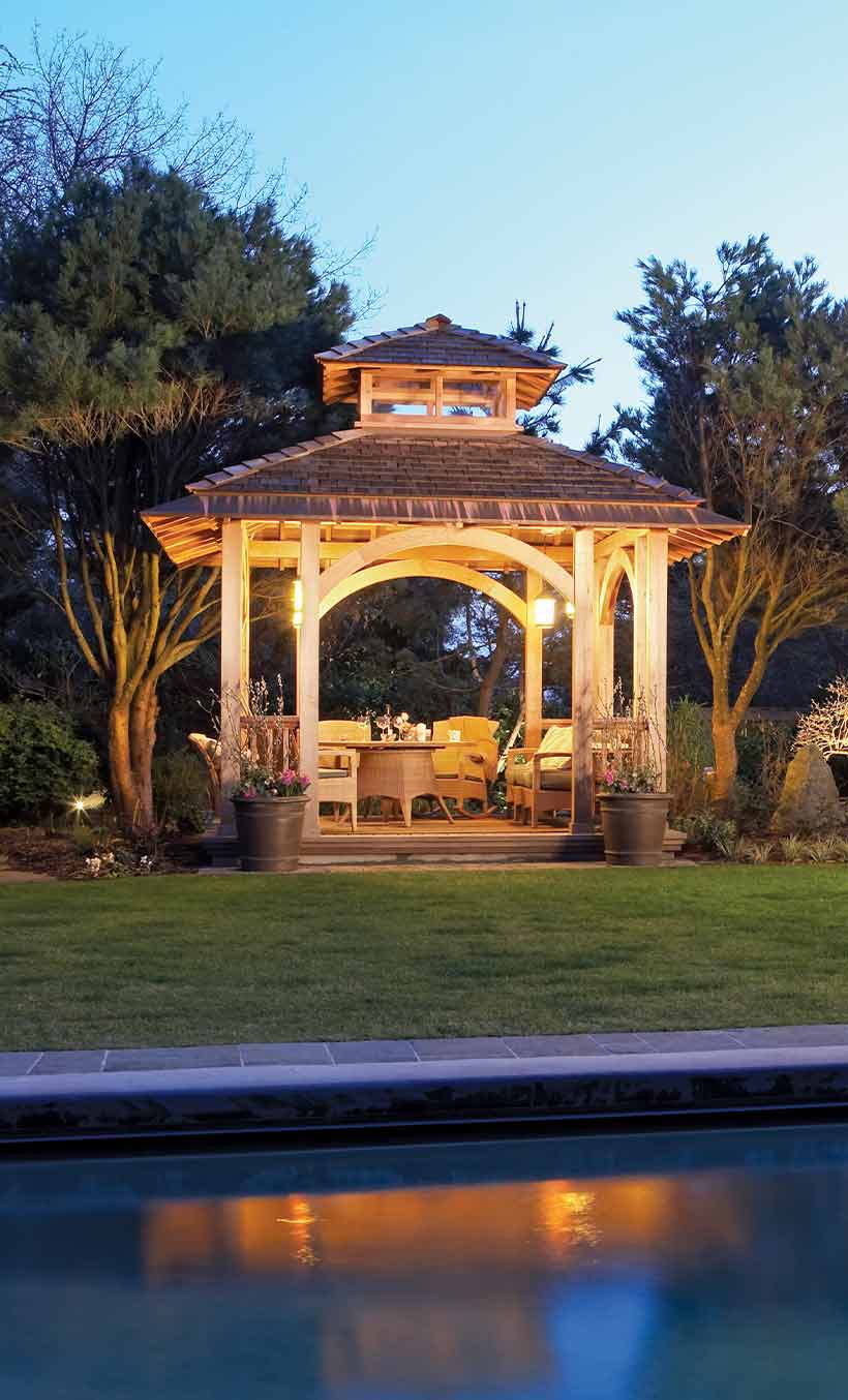 Well-lit outdoor gazebo with landscape lighting at dusk