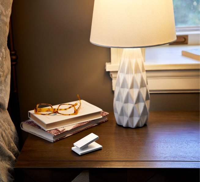 Dimmed lamp with a Pico smart remote on pedestal placed on bedside