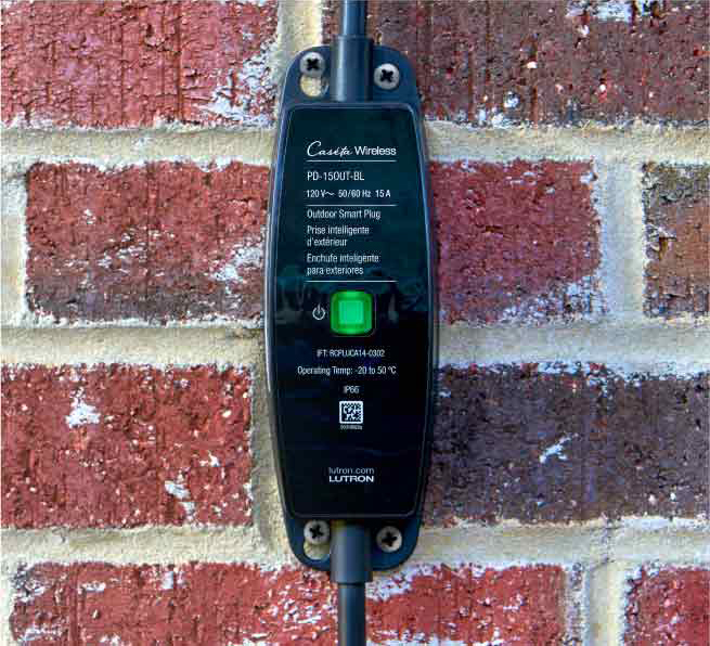 Outdoor smart plug mounted on exterior brick wall