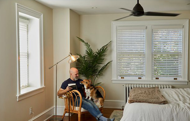 Man reclining on chair with dog and book in his arms besides Pico remote on side table.