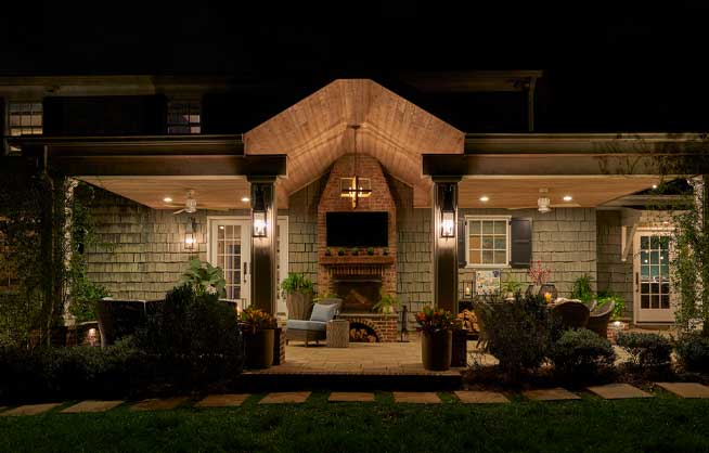 Patio outside house at nighttime, illuminated by lights.