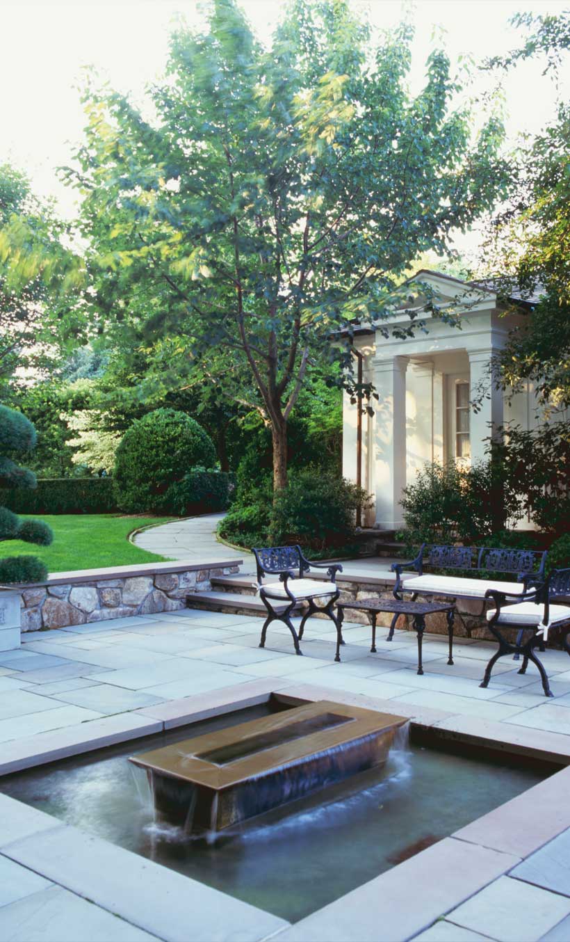 Backyard garden with large pots, trees, and plant beds