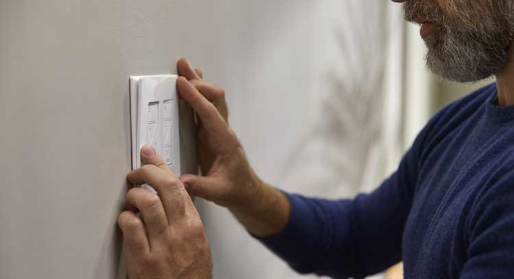 Man installing dimmer light switches on a white wall.