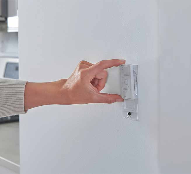 Woman placing a wallplate on wall-mounted Pico remote.