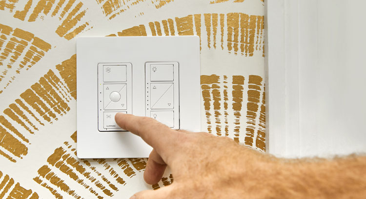 Remote for fans  mounted on a white and metallic gold wallpaper, with a male hand reaching for the controls.