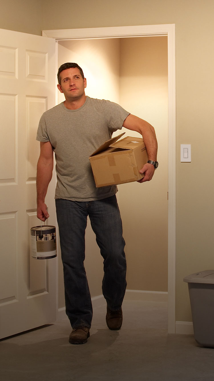 Man carrying basket walking into large, well-lit laundry room